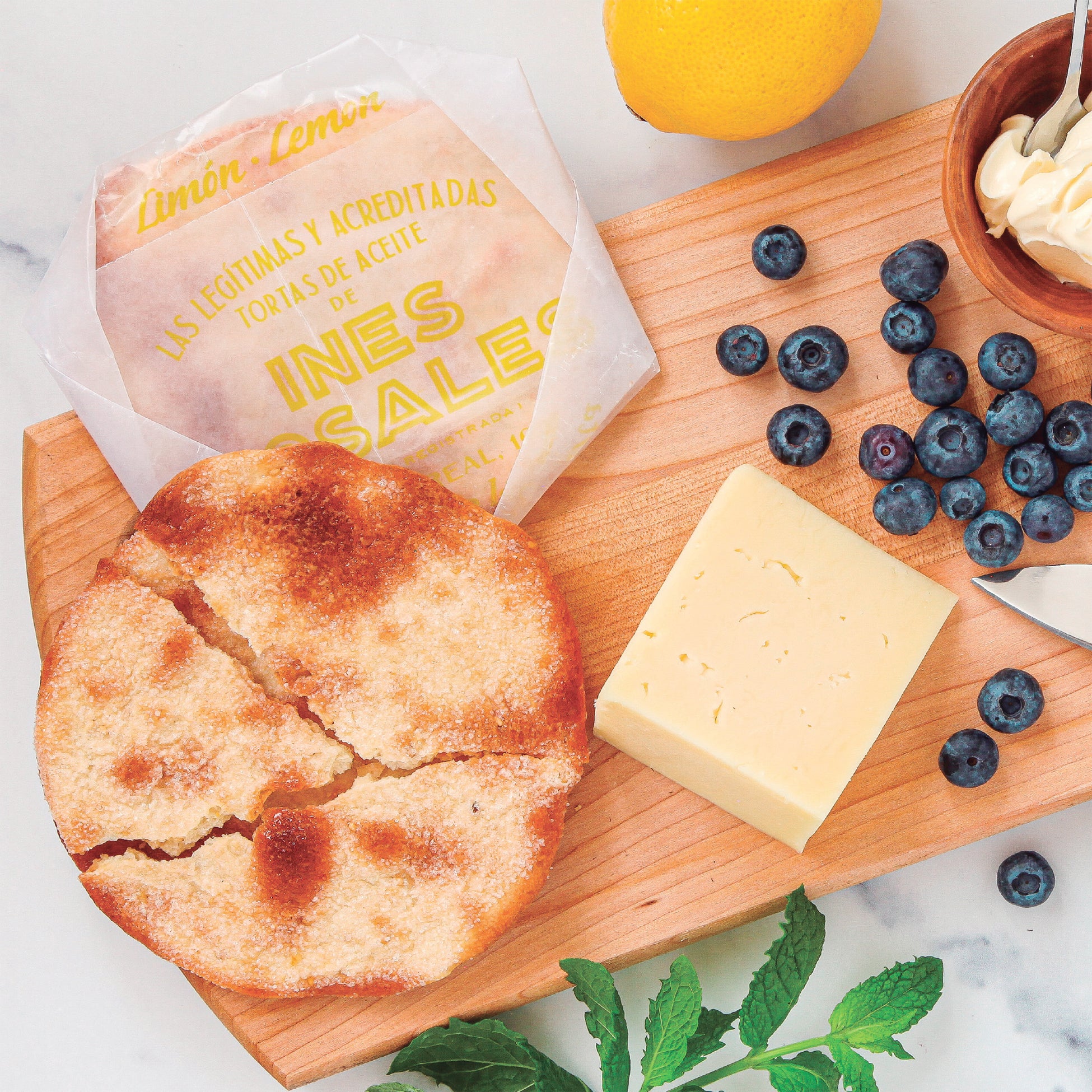 Photo of Candied Lemon Tortas de Aceite Crisps by Ines Rosales on a board with fruit and cheese
