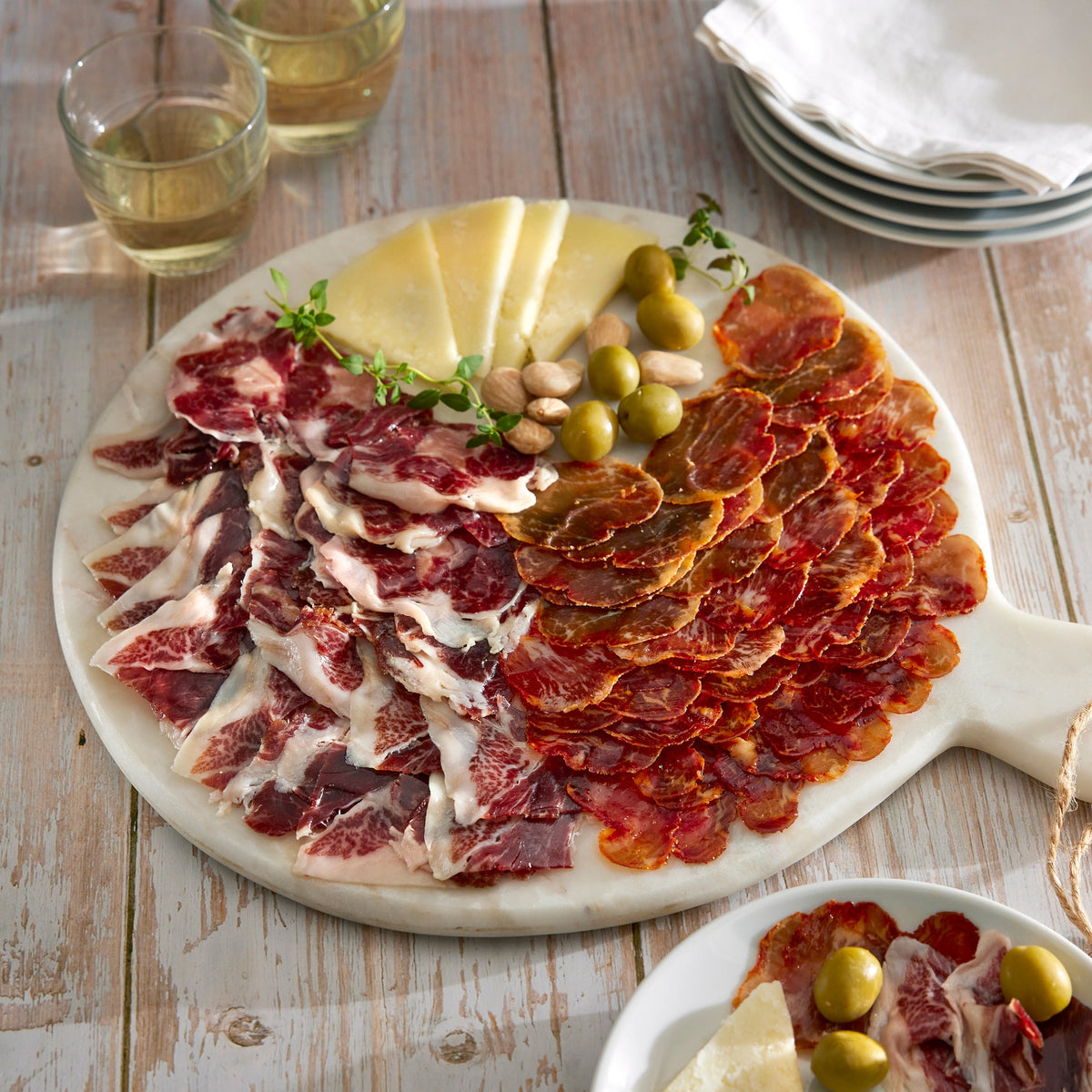 Photo of Duo of Sliced Cinco Jotas Iberico de Bellota Loin and Shoulder arranged on a board with cheese and olives