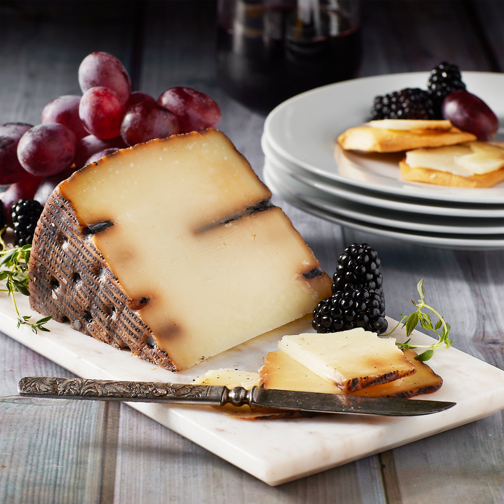 Photo of a wedge of Black Garlic Cheese by Campollano on a board with fruit