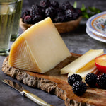 Photo of  a wedge of Young Manchego Cheese by Villajos on a wooden board with fruit