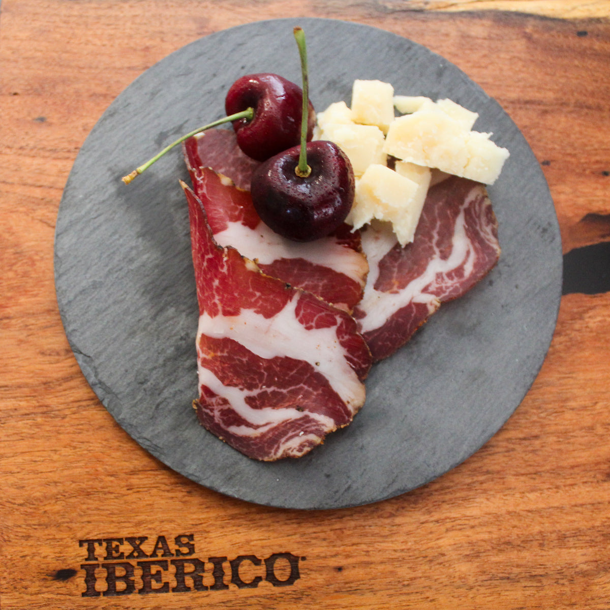 Photo of Texas Iberico Coppa on late with pieces of cheese and cherries