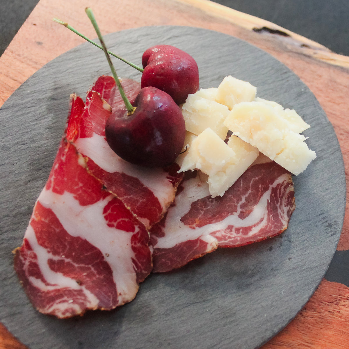 Photo of Texas Iberico Coppa on late with pieces of cheese and cherries